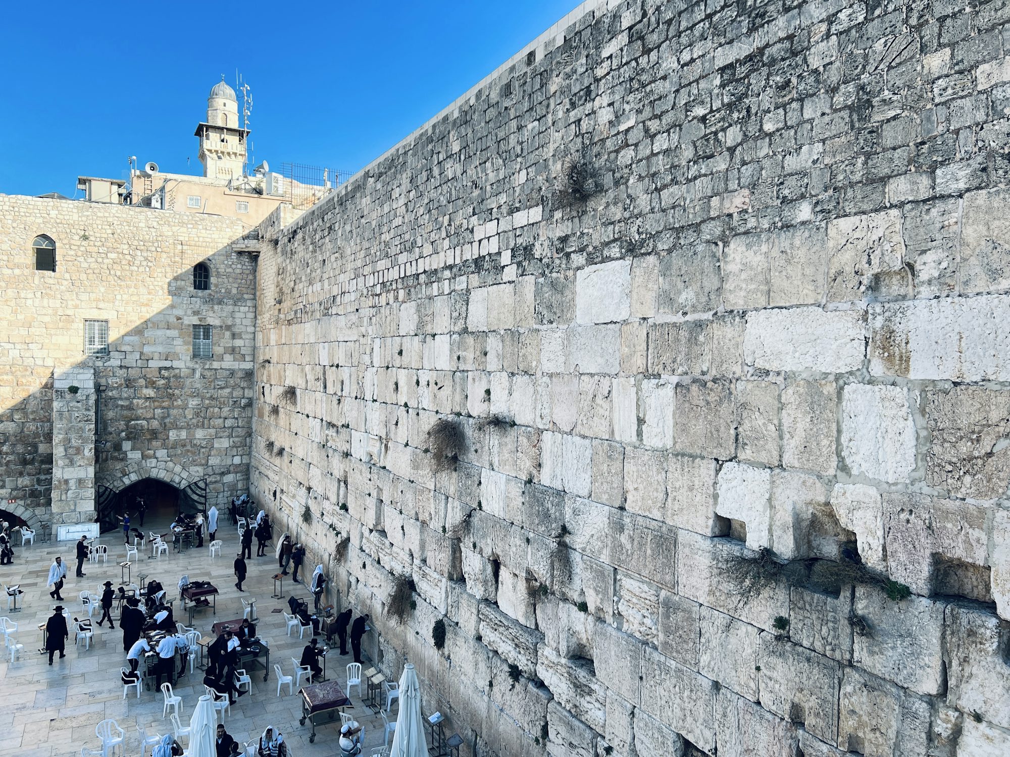 Western Wall in Jerusalem with worshippers in prayer at sunset